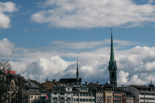 Zurich Switzerland 02 April 2023 View of the city s skyline where the Fraumünster Church spire pierces through the soft blanket of clouds above the rooftops. Zurich Switzerland 02 April 2023 View of the city s skyline where the Fraumünster Church spire pierces through the soft blanket of clouds above the rooftops.