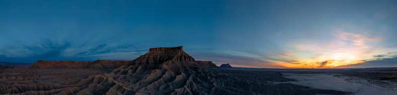 Aerial view of the rugged badlands and dramatic buttes of Caineville at sunset with deep shadows and golden light illuminating the desert landscape in Caineville Utah United States.