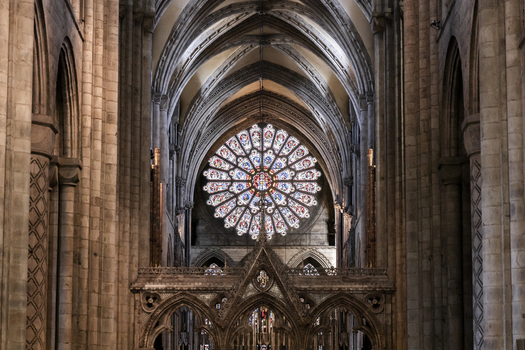View of the interior of Durham Cathedral featuring the ornate rose window soaring stone arches and intricate gothic architecture in Durham England United Kingdom. View of the interior of Durham Cathedral featuring the ornate rose window soaring stone arches and intricate gothic architecture in Durham England United Kingdom.