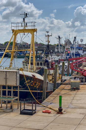 Den Oever Netherlands 18 May 2026 View of British fishing vessels being renovated at the Machinefabriek wharf with workers visible on deck under a cloudy sky.