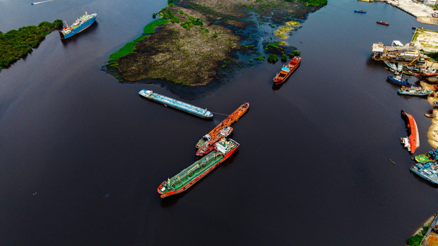 Aerial view of cargo ships and oil tankers navigating the waterways near Satellite Town surrounded by lush mangrove vegetation in Lagos Lagos Nigeria.