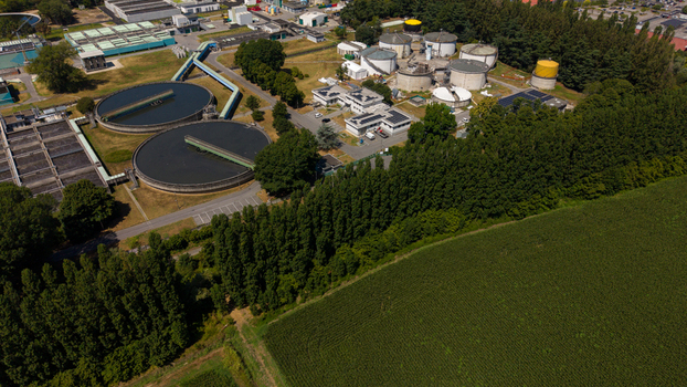 Aerial view of a wastewater treatment plant with circular sedimentation tanks industrial buildings and solar panels surrounded by trees and fields in Milan Lombardy Italy. Aerial view of a wastewater treatment plant with circular sedimentation tanks industrial buildings and solar panels surrounded by trees and fields in Milan Lombardy Italy.
