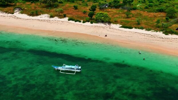 Aerial view of outrigger boat in turquoise water Indonesia.