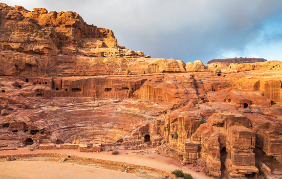 View of the ancient Petra Theatre carved into sandstone cliffs with tiered seating and rock cut architecture Wadi Musa Ma an Governorate Jordan. View of the ancient Petra Theatre carved into sandstone cliffs with tiered seating and rock cut architecture Wadi Musa Ma an Governorate Jordan.