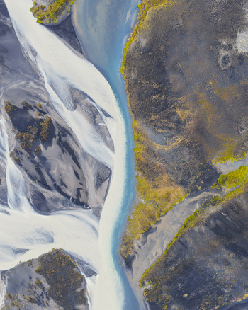 Aerial view of a glacial braided river with intricate sediment patterns dark volcanic sand banks and vibrant green mossy patches in Selfoss Sveitarfelagid Arborg Iceland. Aerial view of a glacial braided river with intricate sediment patterns dark volcanic sand banks and vibrant green mossy patches in Selfoss Sveitarfelagid Arborg Iceland.