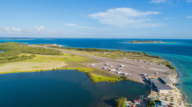 Aerial view of Los Roques archipelago airport with small aircraft on the runway near turquoise Caribbean waters and coastal vegetation in Los Roques Dependencias Federales Venezuela. Aerial view of Los Roques archipelago airport with small aircraft on the runway near turquoise Caribbean waters and coastal vegetation in Los Roques Dependencias Federales Venezuela.