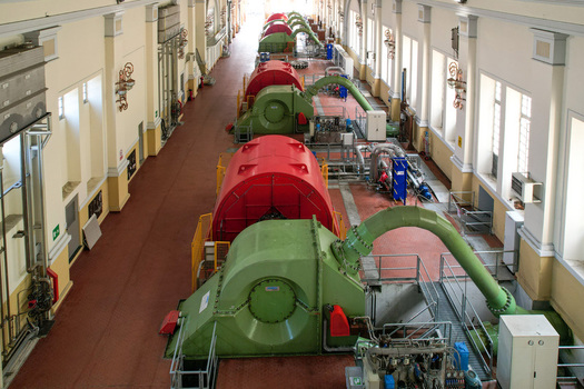 Aerial view of Centrale idroelettrica di Villa featuring large green and red turbines lined up in a spacious industrial hall with high ceilings in Ceresole Reale Piedmont Italy. Aerial view of Centrale idroelettrica di Villa featuring large green and red turbines lined up in a spacious industrial hall with high ceilings in Ceresole Reale Piedmont Italy.