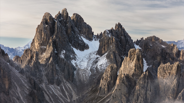 Aerial view of the jagged peaks of the Cadini group with snow in the crevices under a soft sky in Auronzo di Cadore Veneto Italy. Aerial view of the jagged peaks of the Cadini group with snow in the crevices under a soft sky in Auronzo di Cadore Veneto Italy.