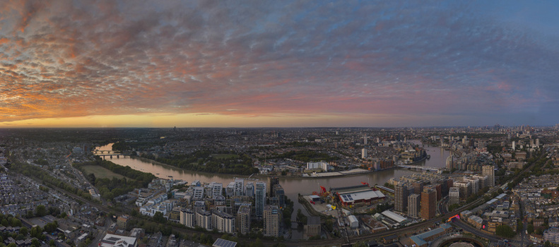 Aerial view of the River Thames in Wandsworth with modern buildings bridges and a vibrant sunset sky over the urban landscape of London England United Kingdom. Aerial view of the River Thames in Wandsworth with modern buildings bridges and a vibrant sunset sky over the urban landscape of London England United Kingdom.