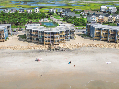 Aerial view of North Topsail Shores beachfront condominiums with sandbag erosion control sandy beach and nearby tennis court in North Topsail Beach North Carolina United States.