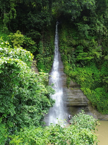 Aerial view of a waterfall cascading down a rocky cliff surrounded by dense green forest with people standing at the base in Sitakund Chittagong Division Bangladesh. Aerial view of a waterfall cascading down a rocky cliff surrounded by dense green forest with people standing at the base in Sitakund Chittagong Division Bangladesh.