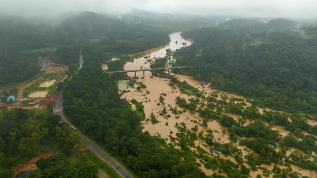 Aerial view of the Sharavathi River flowing through lush green forests with a bridge crossing the water under a cloudy sky in Kargal Karnataka India.