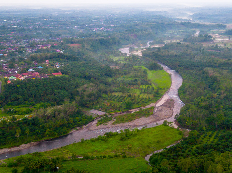 Aerial view of the Taba Tembilang river winding through lush tropical vegetation and green landscapes near the residential outskirts of Arga Makmur Bengkulu Indonesia.