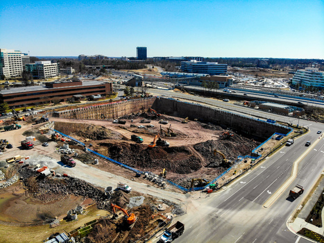 Reston Virginia United States 12 March 2019 Aerial view of a construction site with excavators and dump trucks in a deep pit surrounded by office buildings and a highway. Reston Virginia United States 12 March 2019 Aerial view of a construction site with excavators and dump trucks in a deep pit surrounded by office buildings and a highway.