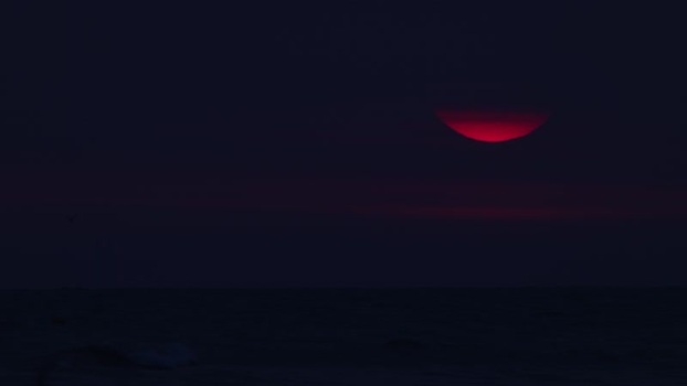View of a dark sky with a red partial sun France.