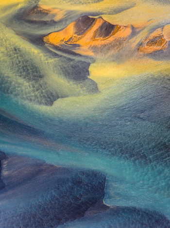 Aerial view of a glacial river delta with intricate patterns of sediment blue glacial water and dark volcanic sand in Iceland. Aerial view of a glacial river delta with intricate patterns of sediment blue glacial water and dark volcanic sand in Iceland.