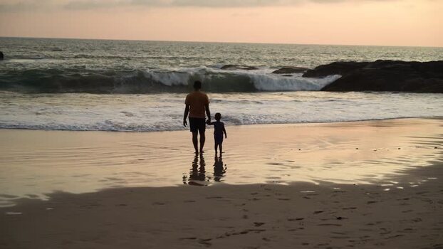 View of a father and son holding hands on a beach Sri Lanka. View of a father and son holding hands on a beach Sri Lanka.