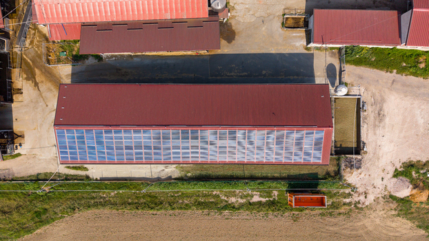 Aerial view of a dairy farm featuring a large barn with solar panels on the roof surrounded by agricultural fields in San Giuliano Milanese Lombardy Italy.