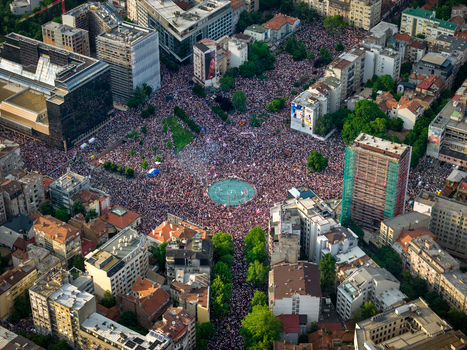 Aerial view of a massive crowd gathered in the central square of Belgrade surrounded by dense urban architecture historic buildings and green trees in Belgrade City of Belgrade Serbia. Aerial view of a massive crowd gathered in the central square of Belgrade surrounded by dense urban architecture historic buildings and green trees in Belgrade City of Belgrade Serbia.
