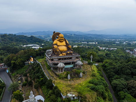 Aerial view of the giant golden Buddha statue situated on a hill surrounded by lush greenery and trees in Jiuru Township Pingtung County Taiwan. Aerial view of the giant golden Buddha statue situated on a hill surrounded by lush greenery and trees in Jiuru Township Pingtung County Taiwan.