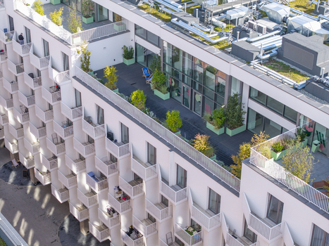 Aerial view of a modern residential building with white balconies a rooftop terrace with lush greenery and mechanical equipment on the roof in Krakow Lesser Poland Voivode Poland.