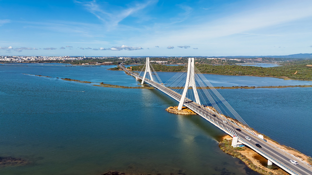 Aerial view of the Arade Bridge spanning the Arade River with cable stayed architecture and cars driving across under a clear blue sky in Portimao Faro District Portugal. Aerial view of the Arade Bridge spanning the Arade River with cable stayed architecture and cars driving across under a clear blue sky in Portimao Faro District Portugal.