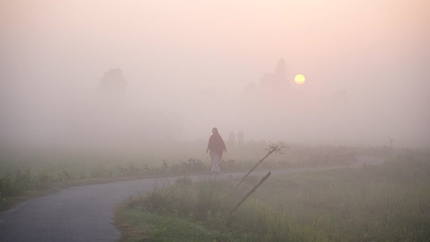 View of a person walking through thick morning fog in Bangladesh.