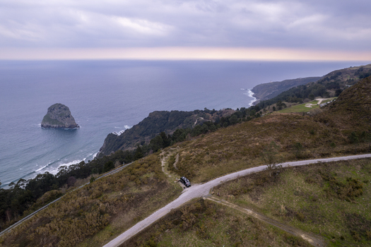 Aerial view of a camper van parked on a dirt road overlooking the rocky coastline and the sea near the hermitage of Gaztelugatxe in Bermeo Euskadi Spain. Aerial view of a camper van parked on a dirt road overlooking the rocky coastline and the sea near the hermitage of Gaztelugatxe in Bermeo Euskadi Spain.