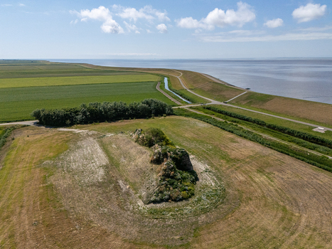 Aerial view of the Dijk van een wijf sculpture situated on a grassy dike overlooking the Wadden Sea with surrounding agricultural fields in Oosterbierum Friesland Netherlands. Aerial view of the Dijk van een wijf sculpture situated on a grassy dike overlooking the Wadden Sea with surrounding agricultural fields in Oosterbierum Friesland Netherlands.