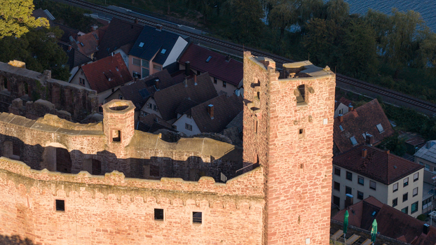 Aerial view of Henneburg castle ruins with red sandstone walls overlooking the town with its traditional rooftops and nearby railway line in Stadtprozelten Bayern Germany. Aerial view of Henneburg castle ruins with red sandstone walls overlooking the town with its traditional rooftops and nearby railway line in Stadtprozelten Bayern Germany.