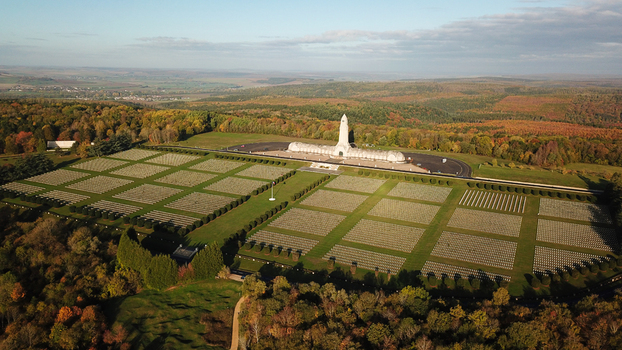 Aerial view of the Douaumont Ossuary memorial and military cemetery with rows of white crosses surrounded by autumn forests in Douaumont Vaux Grand Est France.