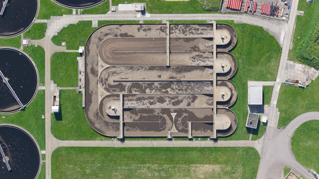 Aerial view of RWZI Geestmerambacht wastewater treatment plant with circular aeration tanks oval basins and industrial infrastructure. Aerial view of RWZI Geestmerambacht wastewater treatment plant with circular aeration tanks oval basins and industrial infrastructure.