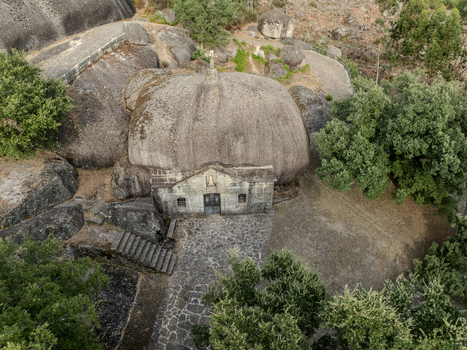 Aerial view of Santuario de Nossa Senhora da Lapa a unique stone chapel built under a massive boulder surrounded by lush trees and rocky terrain in Soutelo Braga Portugal. Aerial view of Santuario de Nossa Senhora da Lapa a unique stone chapel built under a massive boulder surrounded by lush trees and rocky terrain in Soutelo Braga Portugal.