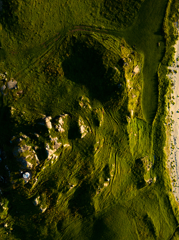 Aerial view of the rugged coastal landscape of Tangstad with green grassy hills and rocky outcrops near the sandy beach in Leknes Nordland Norway. Aerial view of the rugged coastal landscape of Tangstad with green grassy hills and rocky outcrops near the sandy beach in Leknes Nordland Norway.