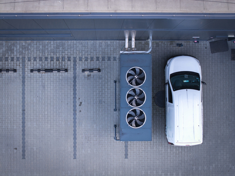 Aerial view of an industrial HVAC unit with three large fans positioned next to a white van in a paved parking lot in Poland. Aerial view of an industrial HVAC unit with three large fans positioned next to a white van in a paved parking lot in Poland.