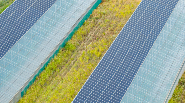 Aerial view of agricultural greenhouses featuring integrated rooftop solar panels for sustainable energy production in Loriol sur Drome Auvergne Rhone Alpes France.