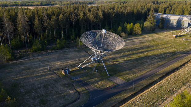 Aerial view of the Westerbork Synthesis Radio Telescope with its large parabolic antenna standing in a field surrounded by dense pine forest in Zwiggelte Drenthe Netherlands. Aerial view of the Westerbork Synthesis Radio Telescope with its large parabolic antenna standing in a field surrounded by dense pine forest in Zwiggelte Drenthe Netherlands.