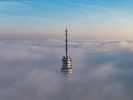 Aerial view of the Roermond TV tower rising above a thick blanket of fog under a clear blue sky at dawn Roermond Limburg Netherlands.