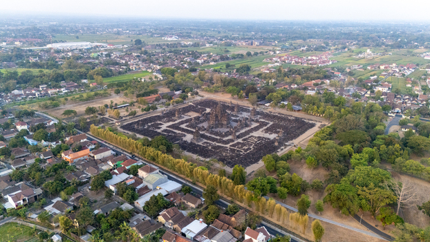 Aerial view of Sewu Temple an ancient Buddhist temple complex with intricate stone structures surrounded by lush greenery and residential areas in Kecamatan Prambanan Jawa Tengah Indonesia.