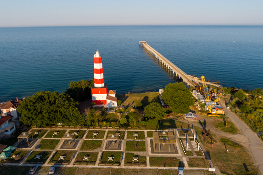 Aerial view of the red and white striped lighthouse a long pier extending into the Black Sea and a landscaped park in Saints Constantine and Helena Varna Bulgaria.