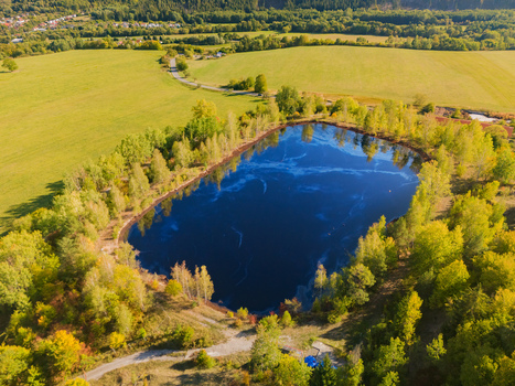 Aerial view of the Gudronove jamy acid tar lagoons surrounded by autumn trees and green fields near the Low Tatras mountains in Predajna Banskobystricky kraj Slovakia. Aerial view of the Gudronove jamy acid tar lagoons surrounded by autumn trees and green fields near the Low Tatras mountains in Predajna Banskobystricky kraj Slovakia.