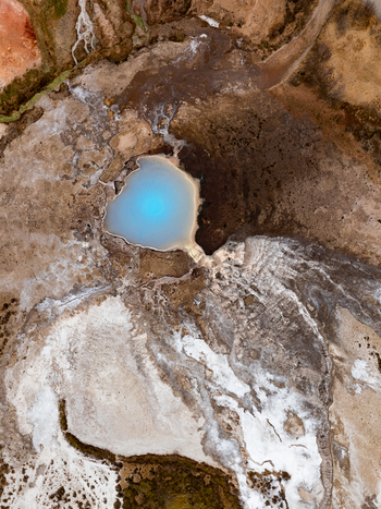 Aerial view of a vibrant blue geothermal pool surrounded by rugged volcanic terrain and mineral deposits in Reykjanesbaer Iceland. Aerial view of a vibrant blue geothermal pool surrounded by rugged volcanic terrain and mineral deposits in Reykjanesbaer Iceland.