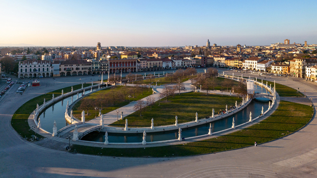 Aerial view of Prato della Valle featuring the elliptical canal and statues surrounded by historic architecture in Padova Veneto Italy.