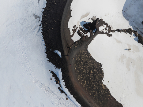 Aerial view of the snowy south slope of Mount Etna featuring dark volcanic rock and a winding path Nicolosi Sicilia Italy. Aerial view of the snowy south slope of Mount Etna featuring dark volcanic rock and a winding path Nicolosi Sicilia Italy.