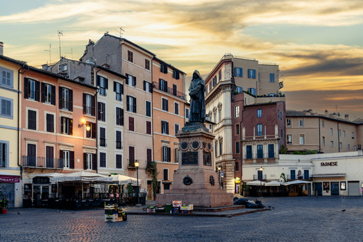 View of the statue of Giordano Bruno in the center of Campo de Fiori square surrounded by historic colorful buildings under a sunset sky in Rome Lazio Italy. View of the statue of Giordano Bruno in the center of Campo de Fiori square surrounded by historic colorful buildings under a sunset sky in Rome Lazio Italy.