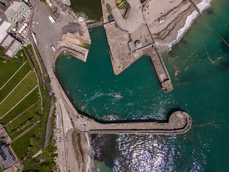 Aerial view of Charlestown Harbour featuring historic stone piers turquoise water and coastal landscape in Charlestown Cornwall United Kingdom. Aerial view of Charlestown Harbour featuring historic stone piers turquoise water and coastal landscape in Charlestown Cornwall United Kingdom.