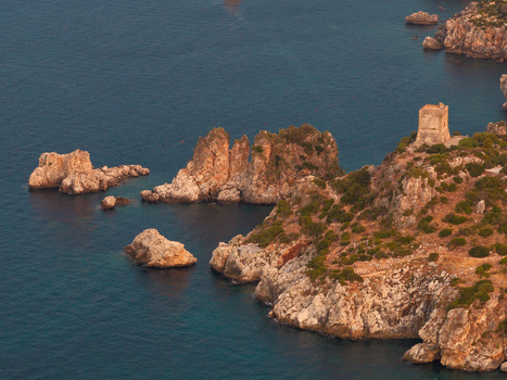 Aerial view of the Riserva Naturale Orientata dello Zingaro featuring a historic watchtower perched on rugged cliffs overlooking the deep blue Mediterranean sea in San Vito Lo Capo Sicilia Italy. Aerial view of the Riserva Naturale Orientata dello Zingaro featuring a historic watchtower perched on rugged cliffs overlooking the deep blue Mediterranean sea in San Vito Lo Capo Sicilia Italy.