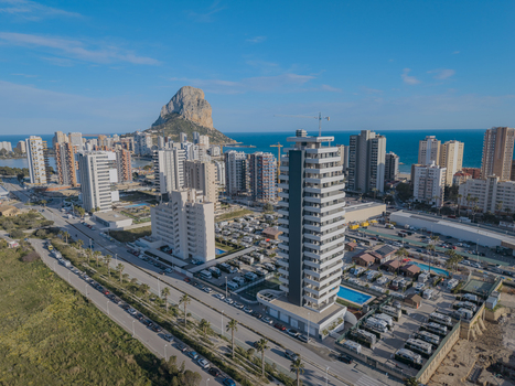 Aerial view of the Penon de Ifach rock formation rising above the coastal city with modern high rise buildings swimming pools and the Mediterranean Sea in Calp Valencian Community Spain. Aerial view of the Penon de Ifach rock formation rising above the coastal city with modern high rise buildings swimming pools and the Mediterranean Sea in Calp Valencian Community Spain.