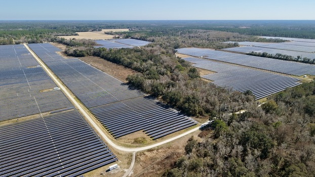 Aerial view of vast solar panel arrays gleaming under the sun s embrace contrasting with the rustic textures of the surrounding woodlands Elkton Florida United States. Aerial view of vast solar panel arrays gleaming under the sun s embrace contrasting with the rustic textures of the surrounding woodlands Elkton Florida United States.