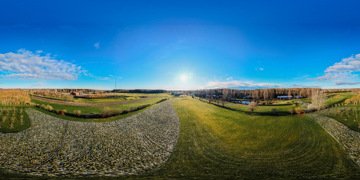 Aerial view of a golf course covered in early morning frost with patches of green grass and surrounding trees under a clear blue sky in Valmiera Valmiera Latvija.